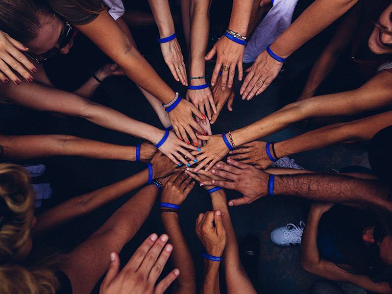 Many peoples hands in a circle all touching in the center